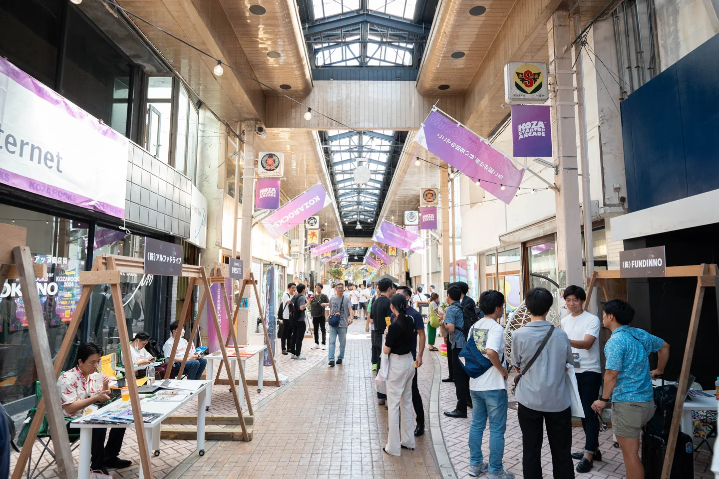 昼のアーケードに並ぶ企業の展示と来場者