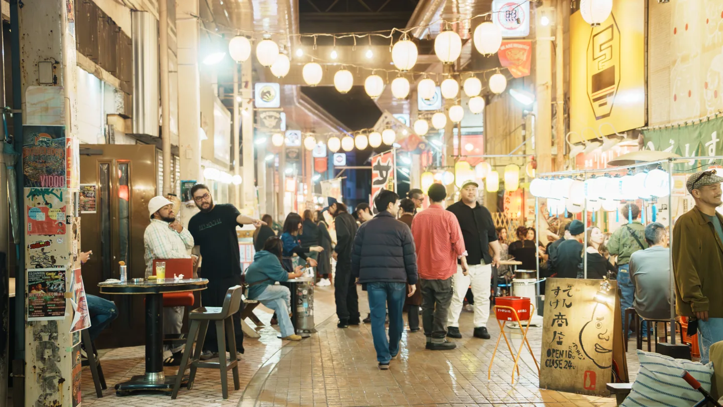 夜の商店街で食事や会話を楽しむ人々
